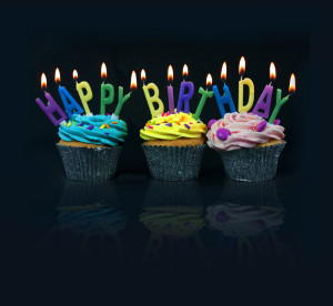 Cupcakes spelling out happy birthday on a black background with reflection